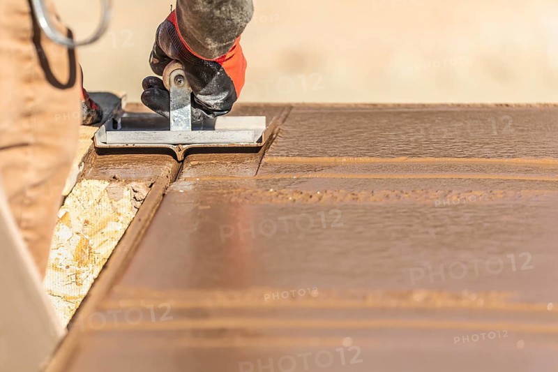 Construction Worker Using Hand Groover On Wet Cement Forming Coping Around New Pool