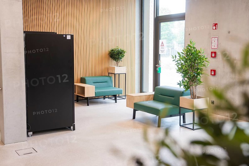 Inviting modern seating area with green sofas and wooden wall, Boarding House des Klinikverbund Südwest, Böblingen, Germany