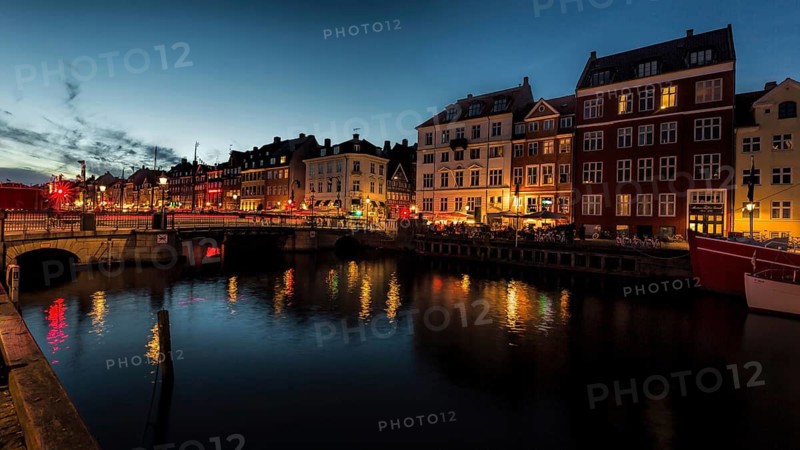 Stimmungsvolle Abendaufnahme eines Kanals mit beleuchteten, alten Gebäuden, Kopenhagen, Dänemark, Nyhavn