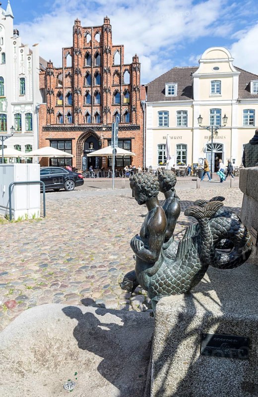 2 mermaids as figures at water art on the market square, in the background the distinctive façade of the Swedish House, Hanseatic City of Wismar, Mecklenburg-Western Pomerania, Germany
