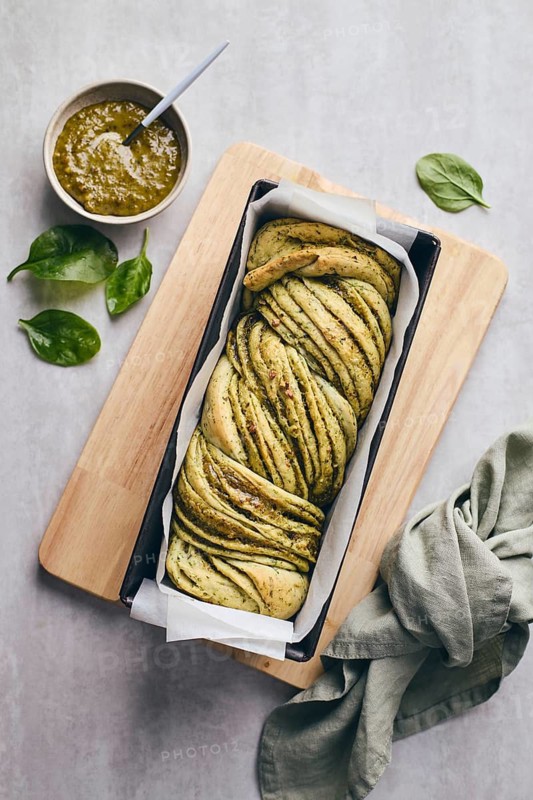 Baked homemade savoury babka plaited bread loaf flavoured with cheese and pesto, in the making tin
