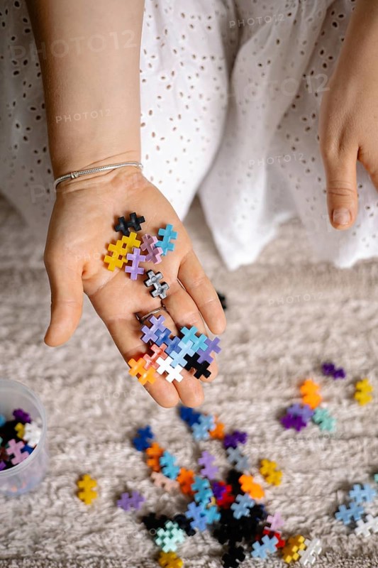 Outstretched hand with colorful puzzle pieces, suggesting creativity and play