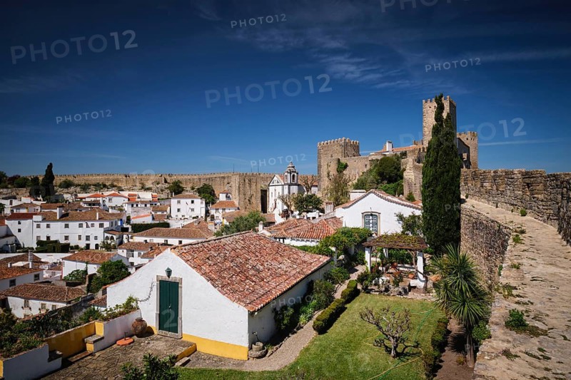 Obidos features a stunning medieval castle overlooking quaint white houses and rooftops in a picturesque Portuguese setting