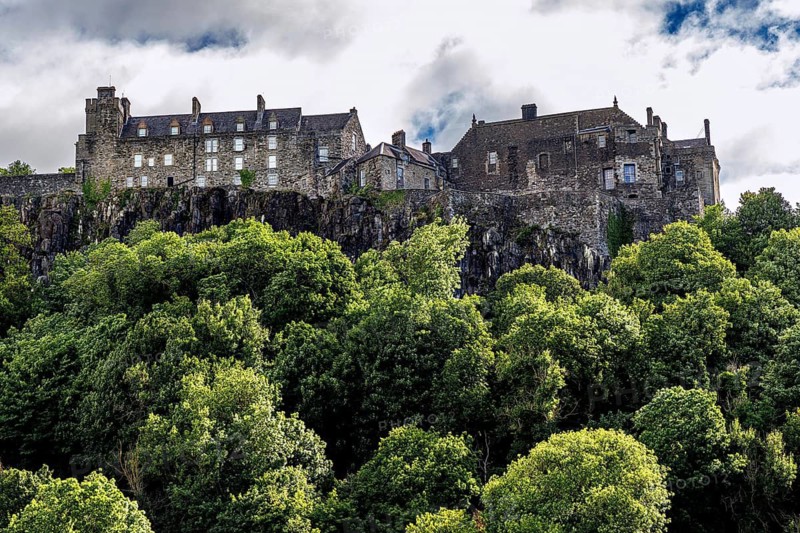 The hilltop Stirling Castle rises above summer woodland on its rocky volcanic crag in Stirling, Scotland, United Kingdom