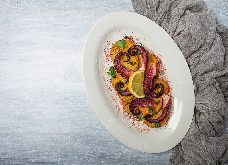 Octopus with potatoes and spices, on a light plate, top view, no people, homemade, close-up