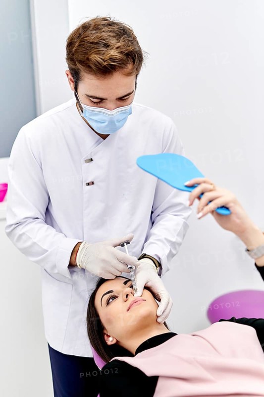 A medical professional in a white coat and sterile gloves administers a hyaluronic acid injection to a patient in a modern medical office, emphasizing precise healthcare procedures