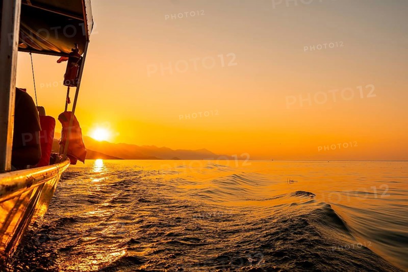 Orange sunset waterside view of Shkoder Lake in Shiroka from a tourist boat. Albania