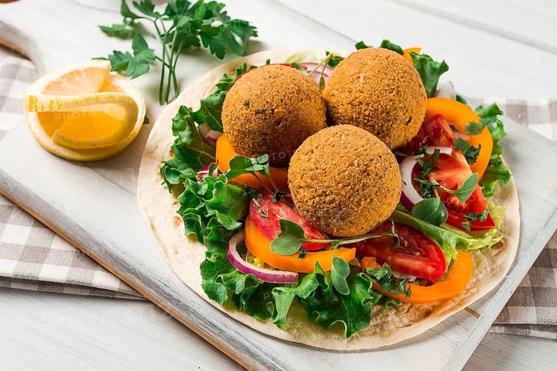 Tortillas, wrapped falafel balls, with fresh vegetables, vegetarian healthy food, on a wooden white background, no people, selective focus.