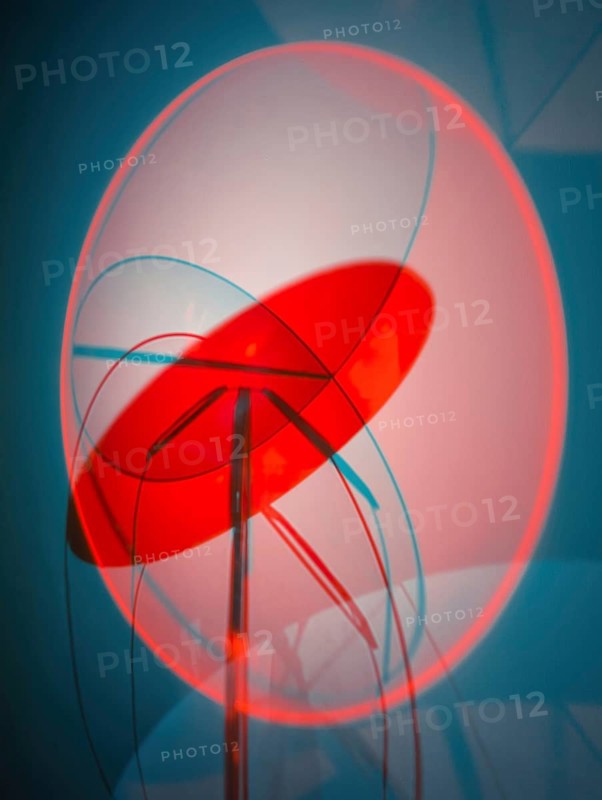 A contemporary abstract sculpture featuring overlapping geometric forms in shades of red and blue, set against a grey background