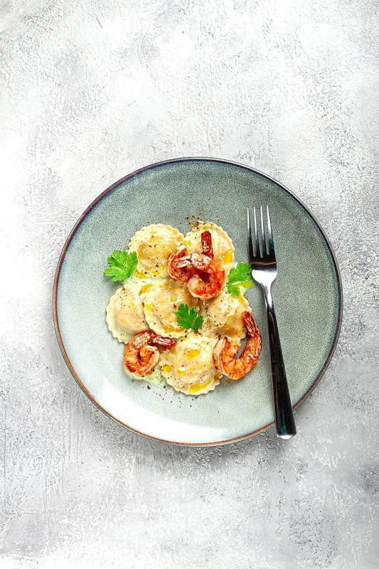 Ravioli with shrimp, in cream sauce, with spices and herbs, top view, no people