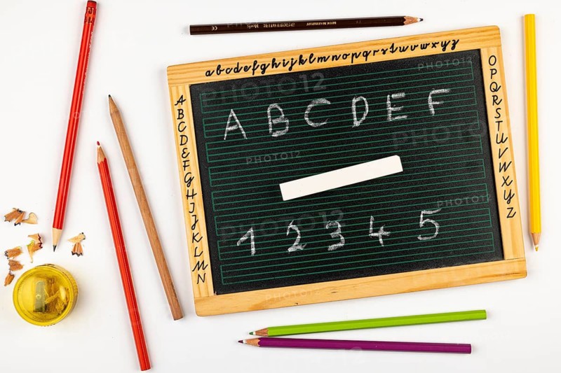 School blackboard with letters, numbers and chalk, pencils and sharpener next to it