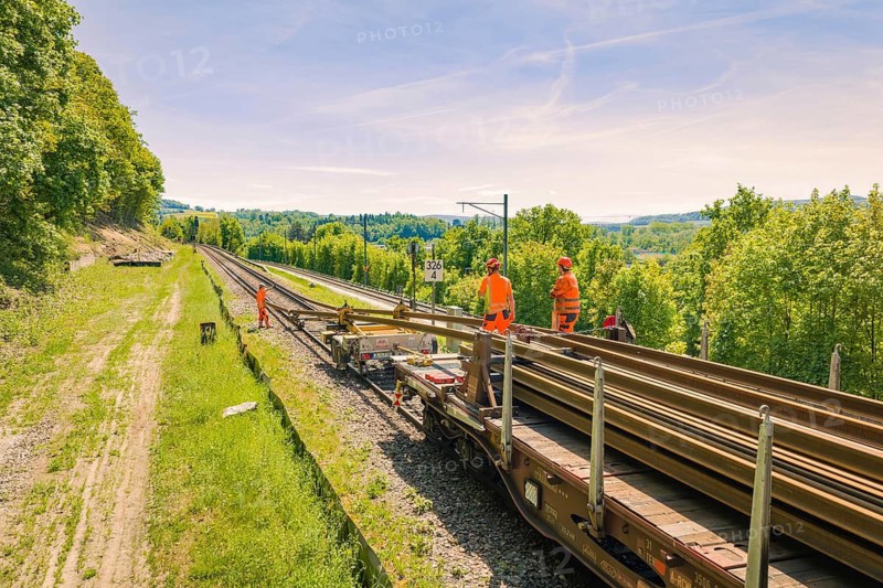 Railway workers working on a railroad car, surrounded by green landscape and blue sky, construction site by Leonhard Weiß to renovate the station and build the overhead line, Waldshut, Germany