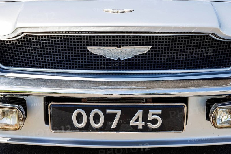 Aston Martin wing badge above a novelty 007 registration plate on a classic car