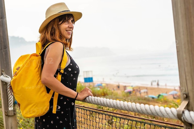 Summer vacation lifestyle. Young adventurous Caucasian girl in a hat enjoying the summer looking at the sea on the beach