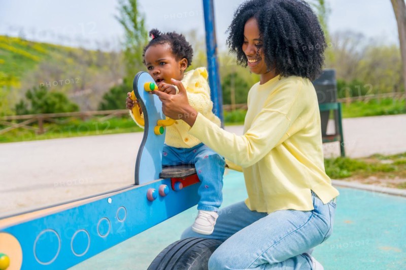 Three quarter length photo of an african mother and little girl playing in the playground