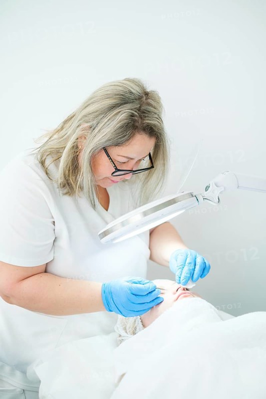An esthetician cosmetologist uses a metal extractor to cleanse pores and remove blemishes for a clearer complexion