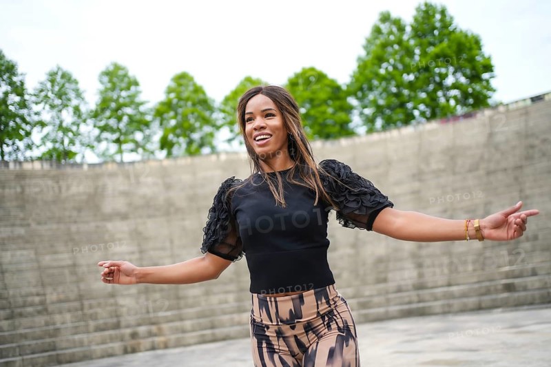 Low angle view photo of a cheerful brunette woman dancing cuban salsa in a park