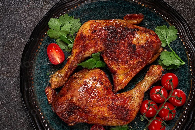 Grilled fried chicken legs, served with fresh cherry tomatoes and herbs, on a plate, homemade, no people