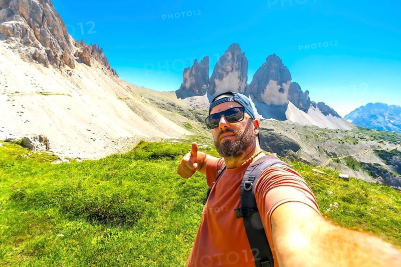 Hiker making thumbs up sign while enjoying the scenic view of tre cime di lavaredo in the italian dolomites during summer