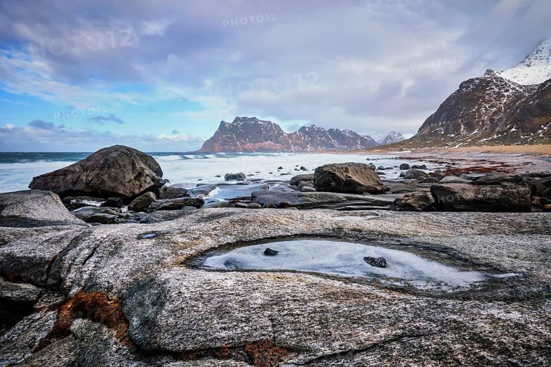 Rocks on beach of fjord of Norwegian sea in winter with snow. Utakliev beach, Lofoten islands, Norway