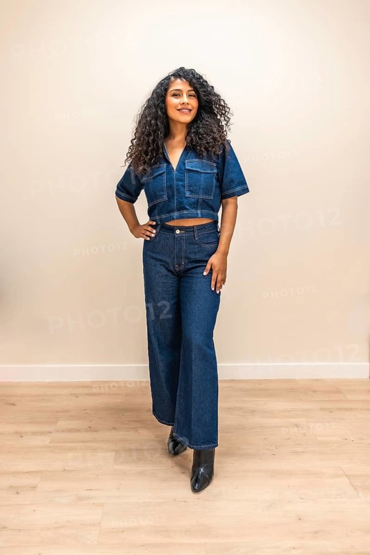 Vertical indoor portrait of a beauty young latin woman standing with denimclothes