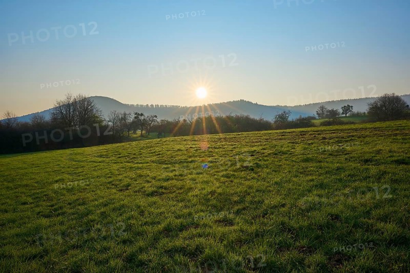 Sun rises over green meadow, hills in the background, Boxtal, Main-Boxtal, Tauber district, Baden-Württemberg, Germany