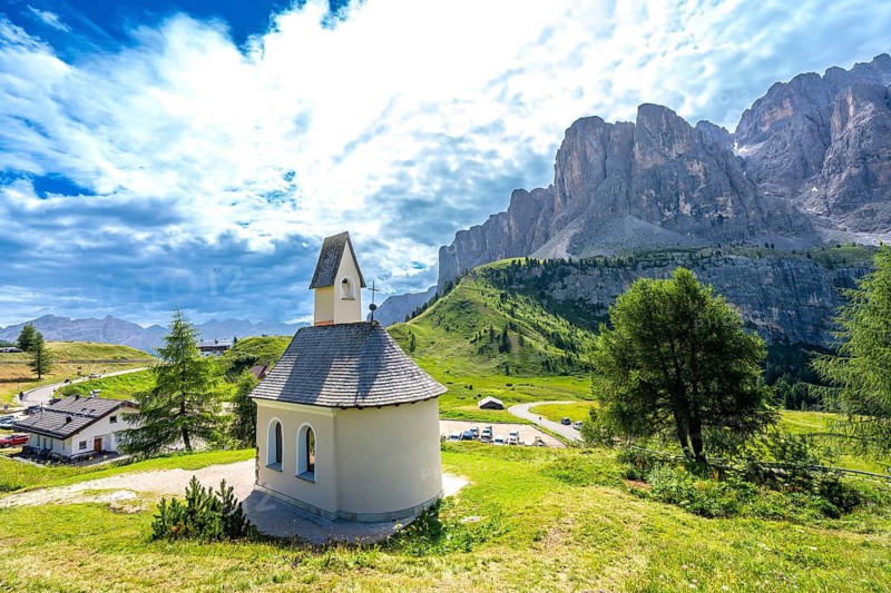 Picturesque chapel nestled in the italian alps, with the breathtaking dolomites mountain range rising in the background on a sunny summer day