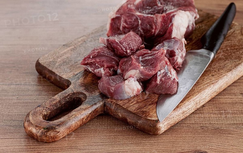 Raw beef meat, sliced on a cutting board, with a knife, no spices, no herbs, top view, wooden table, homemade, no people