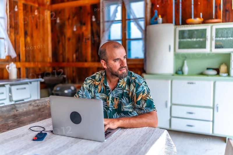 Digital nomad working on laptop in a rustic wooden cabin, embracing the freedom of remote work and enjoying a nomadic lifestyle