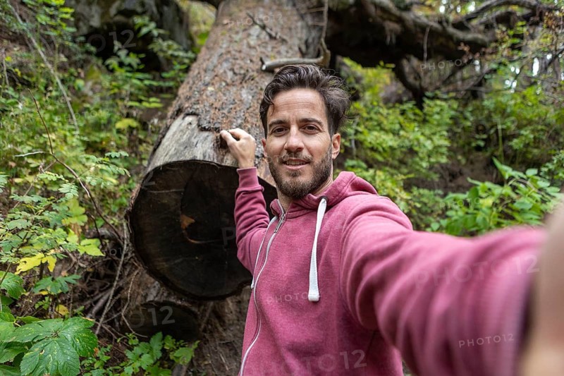 A man enjoys a tranquil walk through the vibrant autumn landscape in Switzerland, surrounded by colorful foliage and serene nature, capturing with a selfie the essence of fall