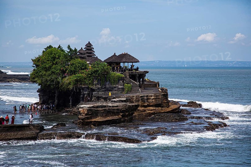 A traditional temple on a rock on the coast surrounded by sea and blue sky, Buddhist water temple Pura Tanah Lot sea temple, Banjar Tanah Lot, Bali, Indonesia