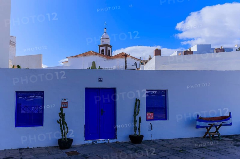 Lanzarote, Canary Islands, Spain, Europe, house in Arrecife, white building front with blue doors, a church tower in the background under a clear sky