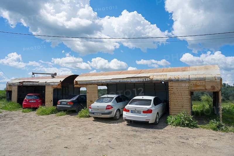 Several cars in makeshift garages under a blue sky with white clouds and rural surroundings, old railroad cars converted into garages, rusty open wagons with cars, Comrat, Komrat, capital of the autonomous region of Gagauzia, Republic of Moldova, Moldova