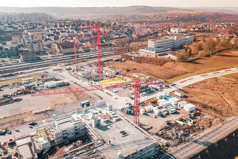 Aerial view of a construction site with several red cranes surrounded by an urban landscape, new Mühlacker nursing home, Enzkreis, Germany