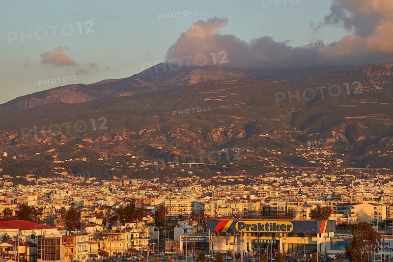 City panorama with mountains and a commercial building in the foreground in the evening light, Patras, Peloponnese, Greece