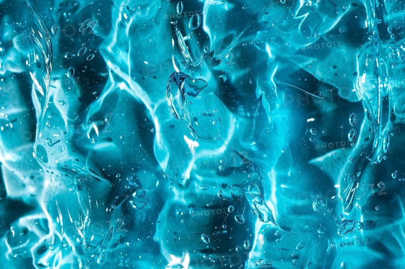 Close-up of vibrant blue gel texture, showcasing smooth, glossy surfaces and encapsulated bubbles. The image captures fluid motion and organic patterns, creating a soothing, modern aesthetic