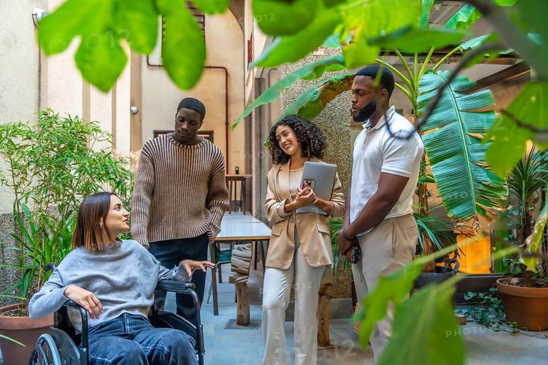 Full length photo of group of diverse colleagues talking in the patio of a modern coworking