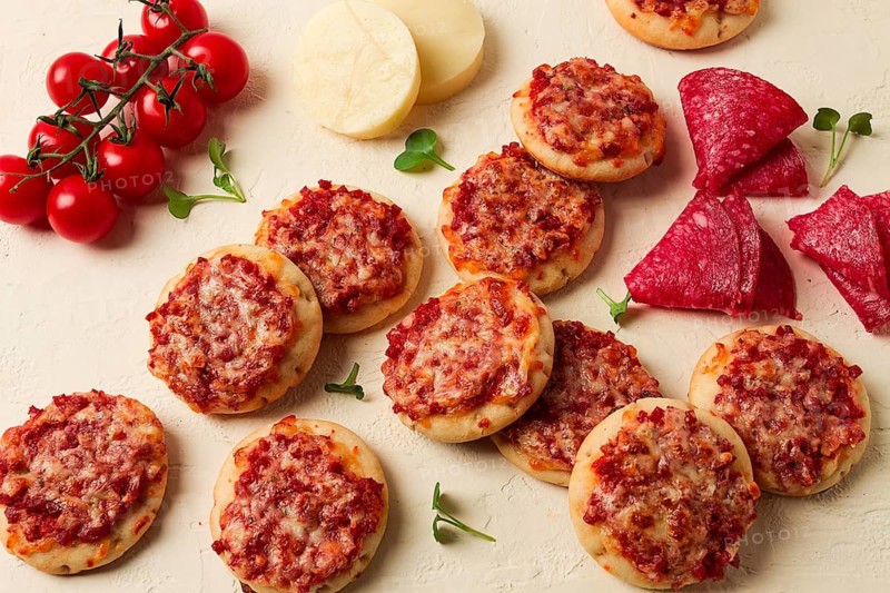 Mini pizzas, salami with mozzarella cheese, on a white table, top view, no people