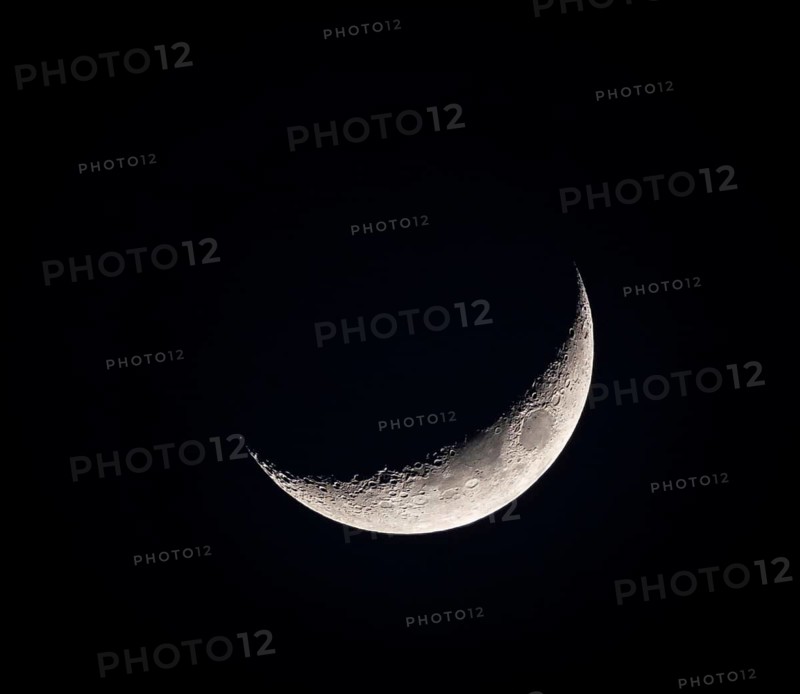 A close-up of a crescent moon against the dark night sky, showcasing the moon's detailed surface and the stark contrast between light and darkness