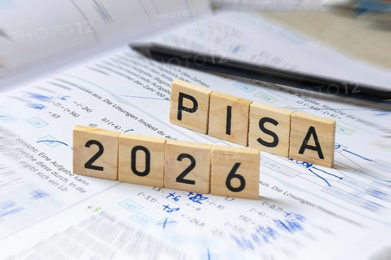 Wooden letters on a math textbook indicate PISA 2026