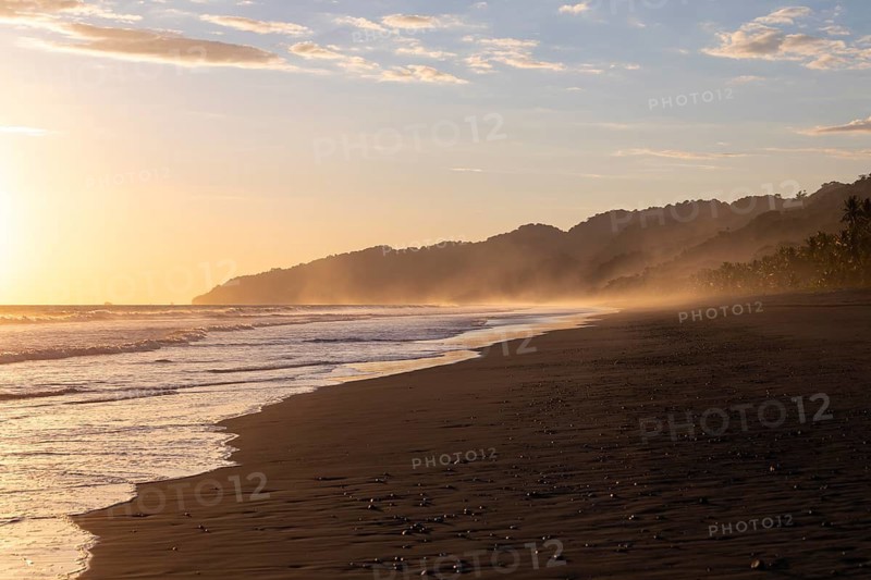 The low sun's golden light illuminates the ocean spray on Carate Beach, with views of Corcovado NP at sunset. Costa Rica