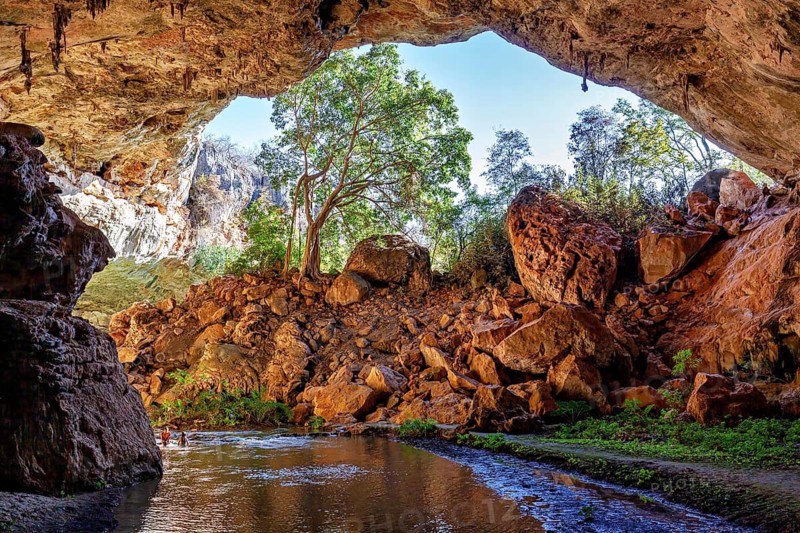 Natural cave arch with a view of trees and rocks in sunlight, The Gruta do Sumidouro in Campo Formoso in the state of Bahia Brazil