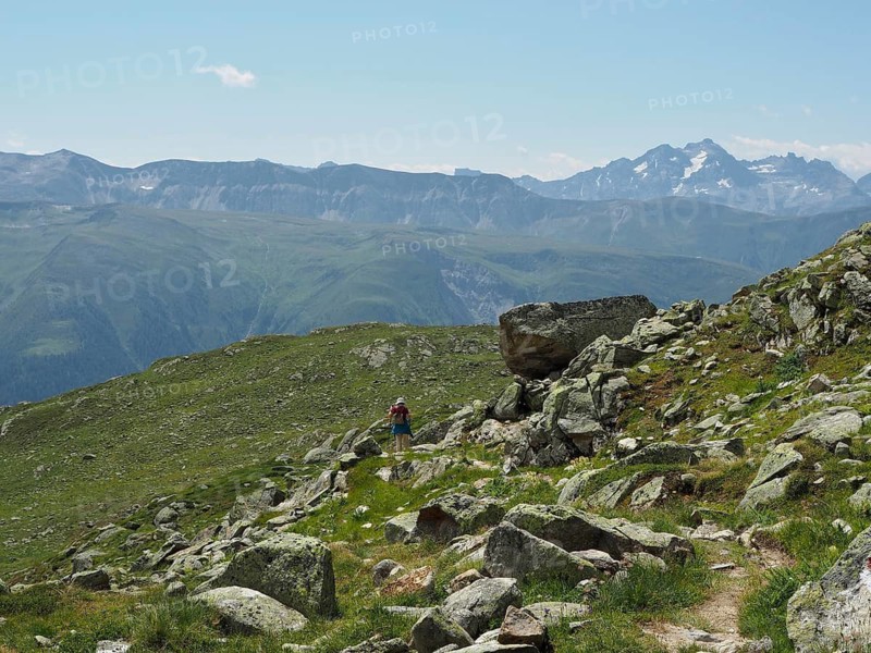 A person hikes on a rocky path through the impressive alpine landscape with majestic peaks, Bellwald, Goms, Canton of Valais, Switzerland