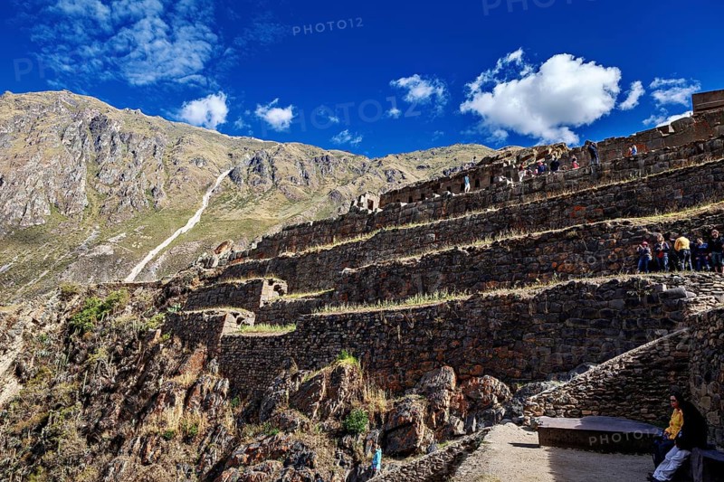 Inca ruins with terraces in a steep mountain landscape under blue skies, The Inca ruins of Ollantaytambo in the Andes of Peru