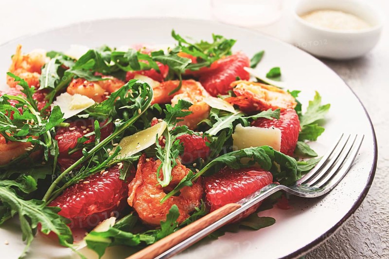 Fresh shrimp salad with arugula, grapefruit, and parmesan served in a bowl