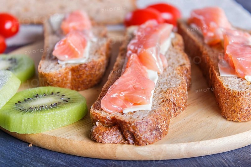 Smoked salmon sandwiches with butter on dark wooden background. cherry tomatoes. close up