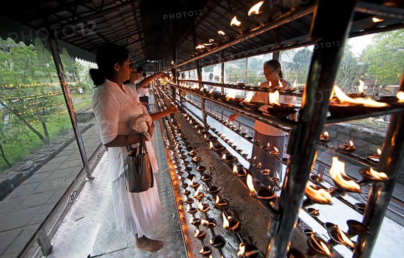 Sri Lankan pilgrims pour oil into candle holders at the Buddhist Temple of the Tooth or Sri Dalada Maligawa, Kandy, Central Province, Sri Lanka