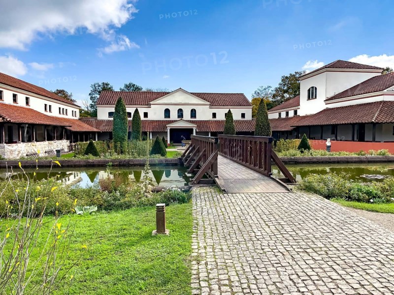 View from site of archaeological open-air museum across small wooden bridge across ornamental pond to reconstructed main building Manor House of Archaeological Park Römische Villa Borg, Perl, Saarland, Germany