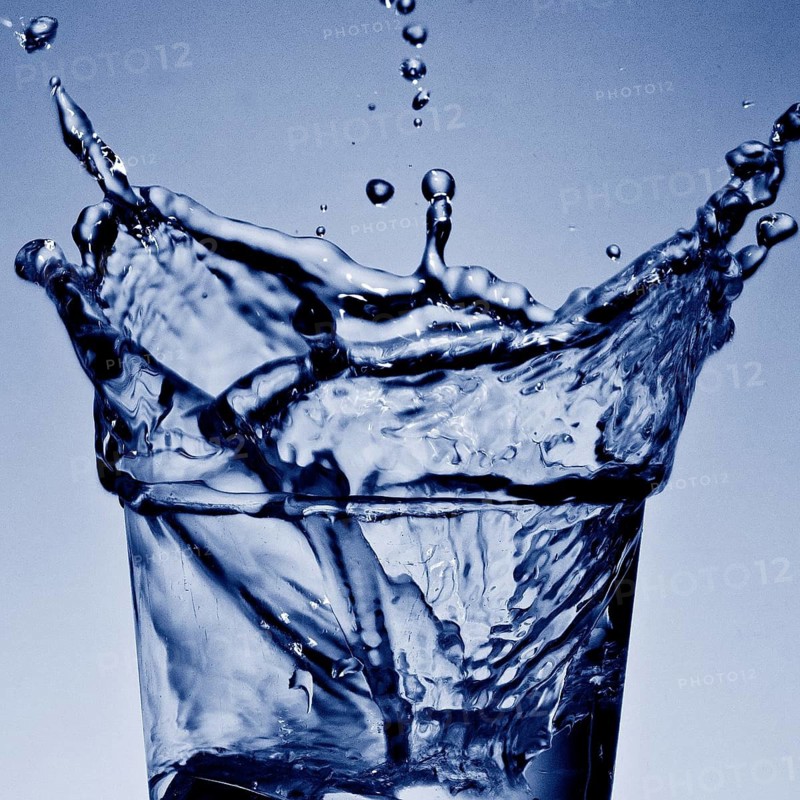 An ice cube cube falls into a glass of cool water, sparkling refreshment in blue duplex toning