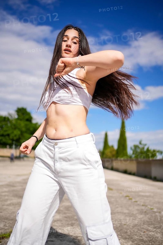 Vertical photo of a young female caucasian student performing dancehall street dance on a park